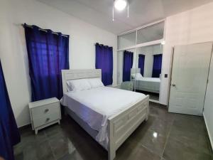 - une chambre avec un lit blanc et des rideaux bleus dans l'établissement La casa blanca, à Río San Juan