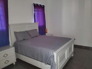 - une chambre avec un lit blanc et des rideaux violets dans l'établissement La casa blanca, à Río San Juan