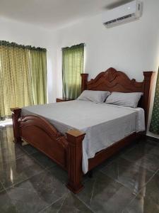 - une chambre avec un grand lit en bois dans l'établissement La casa blanca, à Río San Juan