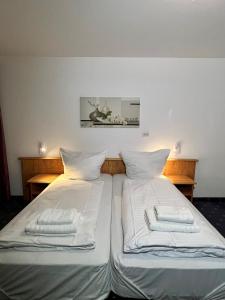 um quarto com 2 camas com lençóis brancos e almofadas em Hotel Neo Cologne Bonn Airport em Rösrath