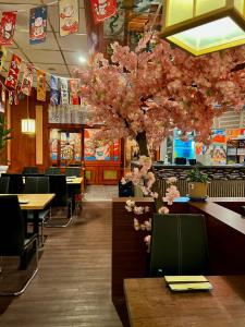 a restaurant with tables and a tree with pink flowers at Hotel Neo Cologne Bonn Airport in Rösrath