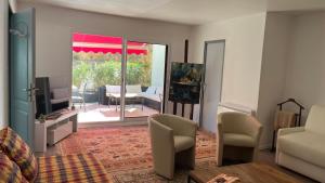 ein Wohnzimmer mit einem Sofa und Stühlen sowie eine Terrasse in der Unterkunft Trés belle suite prés mer et golf avec piscine in Saint-Côme