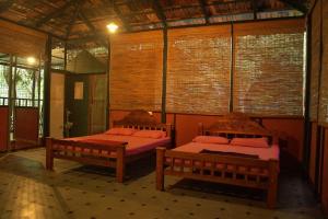 a room with two beds in a building with windows at Rancho Farmstay in Sultan Bathery