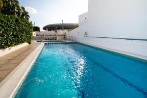 - une piscine d'eau bleue à côté d'un bâtiment dans l'établissement Hotel Tarba, à Sant Antoni de Portmany