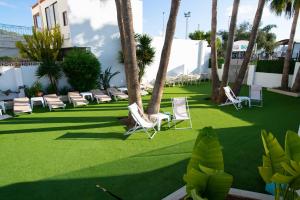 a lawn with chairs and palm trees on it at Hotel Tarba in San Antonio