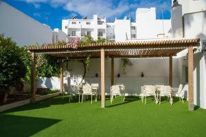 een tuinhuisje met witte stoelen en tafels op een gazon bij Hotel Tarba in San Antonio