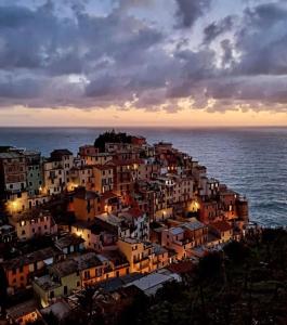 a town on a hill in front of the ocean at night at La Piramide in Manarola