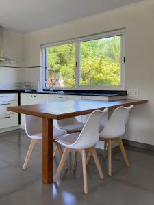 a kitchen with a wooden table and white chairs at Casa Country Altos Arrayanes in Mercedes