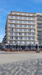 ein großes Gebäude am Strand neben dem Strand in der Unterkunft Hotel Sandeshoved Zeedijk in Nieuwpoort