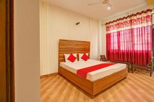 Super OYO Hotel NR Residency في Banūr: غرفة نوم بسرير وستارة حمراء
