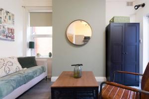 uma sala de estar com um sofá e um espelho em Serene Earlsdon Flat With Smart TV, Wifi & 10 Minute walk to Train Station em Spon End