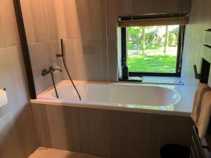 a bath tub in a bathroom with a window at NOUVEAU - Ecolodge avec piscine au Golf-Plage de Biscarrosse - Couchage 2 adultes - Petit-déjeuner compris in Biscarrosse