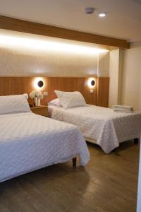 two beds in a hotel room with white sheets at Grand Hotel Santa Ana in Cuenca