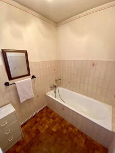 een witte badkamer met een bad en een spiegel bij Jolie maison très calme in Ajaccio