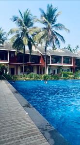a swimming pool with palm trees in front of a building at Luxury apartment Blue lagoon in Goa