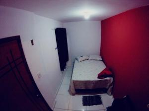 um pequeno quarto com uma pequena cama e uma parede vermelha em Casa do Aventureiro em Abraão