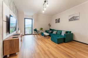 a living room with a green couch and a table at Apartament przy Baszcie - z prywatnym parkingiem w centrum - by SpaceApart in Jelenia Góra
