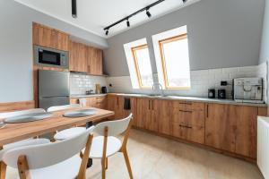 a kitchen with wooden cabinets and a wooden table and chairs at Apartament przy Baszcie - z prywatnym parkingiem w centrum - by SpaceApart in Jelenia Góra