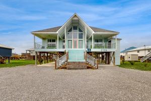 a house with a large front porch on a gravel driveway at Shore Beats Work in Dauphin Island