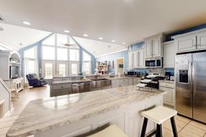 a large kitchen with white cabinets and a large island at Shore Beats Work in Dauphin Island
