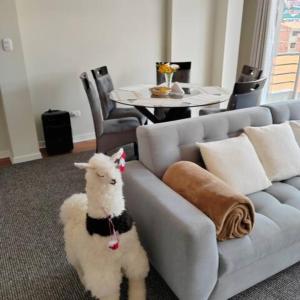 una pecora bianca seduta accanto a un divano in soggiorno di Elite Apartment 2 a Cuzco