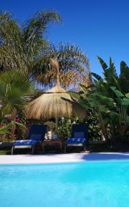 two chairs and a straw umbrella next to a swimming pool at Casa Silca in Marbella