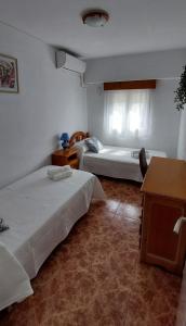 een slaapkamer met 2 bedden, een tafel en een bureau bij Casa Conchi Córdoba in Córdoba