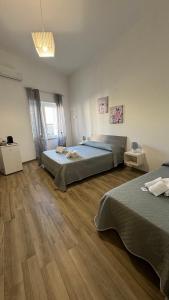 a bedroom with two beds and a wooden floor at Carpentry in Uggiano la Chiesa