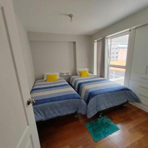 2 Betten in einem kleinen Zimmer mit Fenster in der Unterkunft Elite Apartment 2 in Cusco