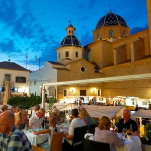 a group of people sitting at tables in front of a building at Casa Roberto Altea in Altea