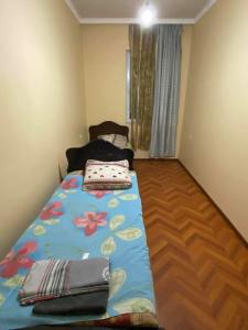 a small bedroom with a bed with a flower blanket at Guest House Gela in Batumi