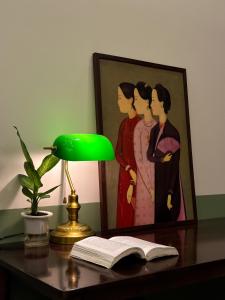 a lamp and an open book on a desk with a painting at A Little Saigon in Ho Chi Minh City