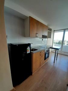 a kitchen with a black refrigerator and wooden cabinets at Tu hogar lejos de casa in Chillán