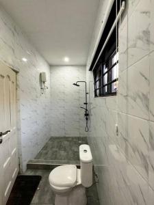 a white bathroom with a toilet and a window at Fully Furnished 1 Bedroom House in Accra