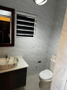 a white bathroom with a toilet and a sink at Fully Furnished 1 Bedroom House in Accra