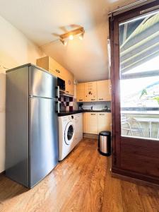eine Küche mit einem Kühlschrank aus Edelstahl sowie einer Waschmaschine und einem Trockner in der Unterkunft 4- Joli studio Brides-les-Bains avec vue montagne in Brides-les-Bains