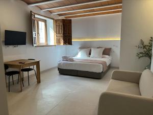 a bedroom with a bed and a table and a couch at Cortijo San Roque Alojamientos Rurales in Puebla de Don Fadrique