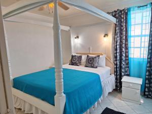 1 dormitorio con cama con dosel y sábanas azules en Peaceful Connexions Condo en Christ Church