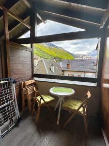 een kleine tafel en stoelen in een kamer met een raam bij 5- Brides-les-Bains Studio de charme avec vue montagne in Brides-les-Bains