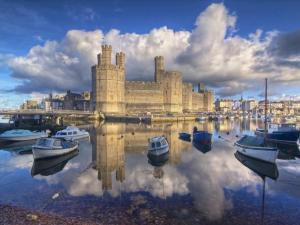a castle with boats in the water in a harbor at Apartment 6 Old Conservative Club in Historic Town Pass the Keys in Caernarfon