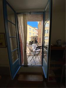 Une porte ouverte s'ouvre sur un balcon avec une table à l'extérieur. dans l'établissement Aux 4 FONTAINES, à Narbonne