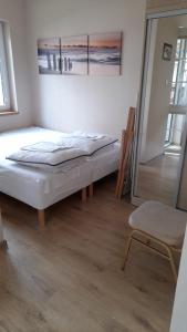 a small bedroom with a bed and a chair at Apartamenty Przy Brzegu in Rowy