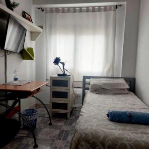 1 dormitorio con cama, escritorio y ventana en Habitación en Sevilla dias/semana, en Camas