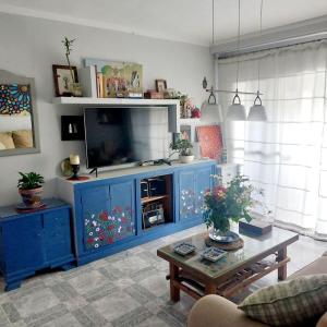 una sala de estar con un centro de entretenimiento azul con TV en Habitación en Sevilla dias/semana, en Camas