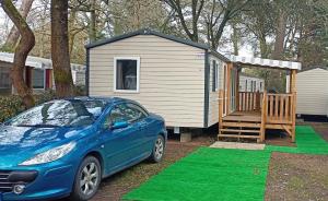 a blue car parked in front of a tiny house at Mobile Home For You les Pierres Couchées in Saint-Brevin-les-Pins
