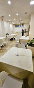 una stanza con tavoli bianchi e sedie e tavoli bianchi di Hotel Palace Masoanri's a Reggio di Calabria