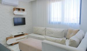 a white living room with a couch and a tv at KRABİ APART in Antalya