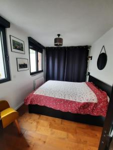 een slaapkamer met een bed met een rood en wit dekbed bij Beauté et Fonctionalité aux Portes de Paris in Meudon
