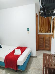 Hotel Sevilla Plaza في بوكارامانغا: غرفة نوم مع سرير مع بطانية حمراء عليه