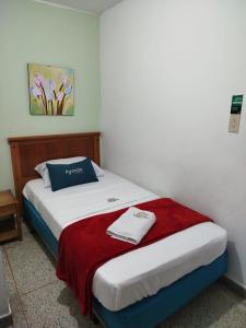 Hotel Sevilla Plaza في بوكارامانغا: غرفة نوم بسرير وبطانية حمراء وبيضاء